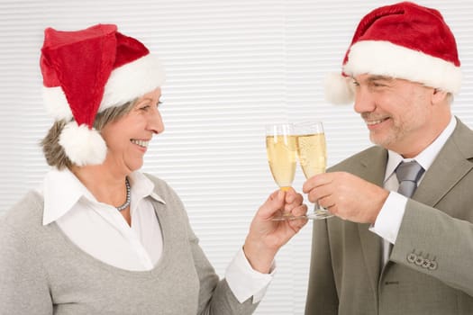 Professional laughing elegant senior businesspeople in Christmas hat drink champagne