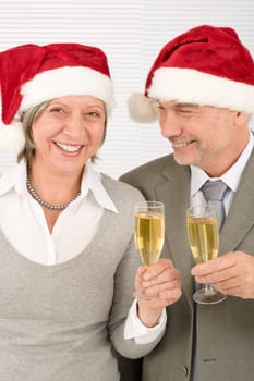 Laughing elegant senior businesspeople in Christmas hat drink champagne