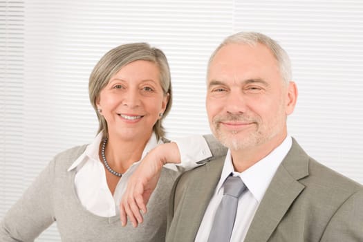 Professional elegant smiling senior businesswoman leaning against her male colleague