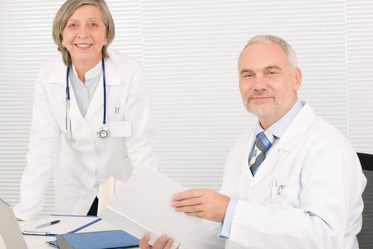 Medical senior doctor male reading book with professional female colleague