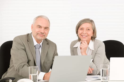 Professional senior businessman pointing at computer with woman colleague discussing