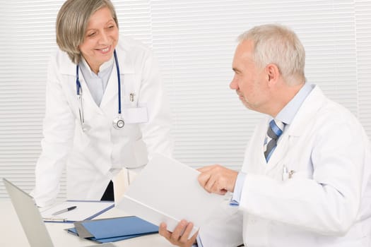 Medical senior doctor male reading book with professional female colleague