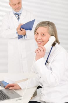 Medical senior doctor female calling with professional male colleague office