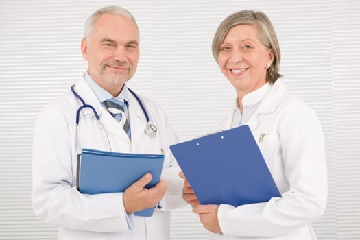 Medical doctor team senior woman and mature man holding folders