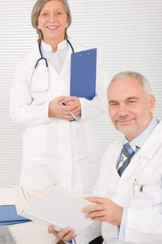Medical senior doctor male reading book with professional female colleague
