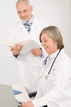 Medical senior doctor female look computer with professional male colleague