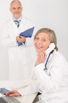 Medical senior doctor female calling with professional male colleague office