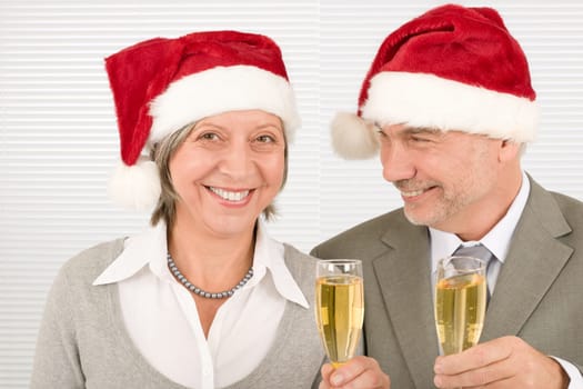 Laughing elegant senior businesspeople in Christmas hat drink champagne