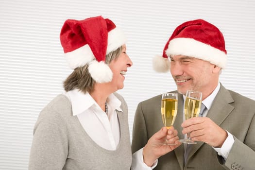 Laughing elegant senior businesspeople in Christmas hat drink champagne