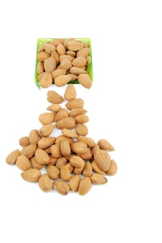 sliding down almond nuts from a green cup isolated on white background