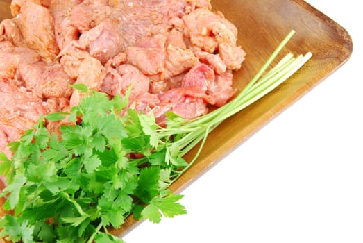 raw pork meat with parsley ready to be cooked on a wooden tray (over white)