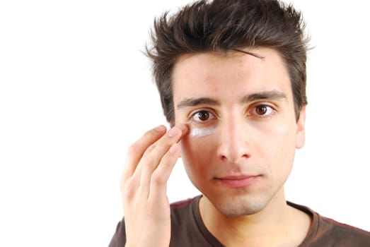 young handsome man applying eye cream (over white background)