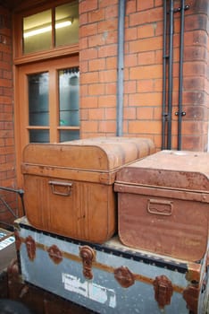 heap of vintage old suitcases in front of a brick wall building