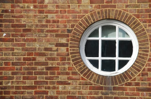 round and vintage wooden window on a brick wall building
