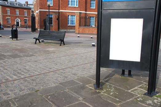 empty billboard at the sidewalk with wooden bench and typical british brick wall buildings