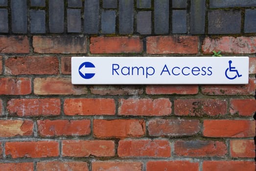 ramp access sign on a brick wall background