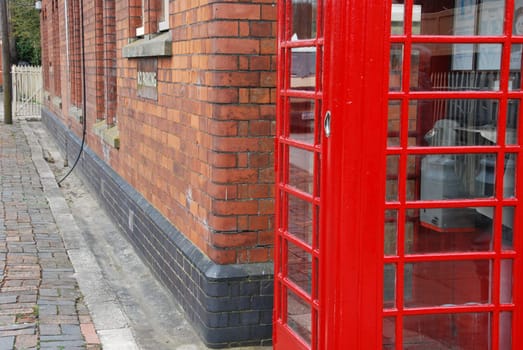 typical red telephone booth and brick wall building on the background