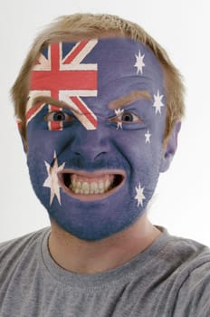 High key portrait of an angry man whose face is painted in colors of australia flag