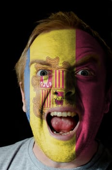 Low key portrait of an angry man whose face is painted in colors of andoran flag