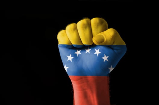 Low key picture of a fist painted in colors of venezuela flag