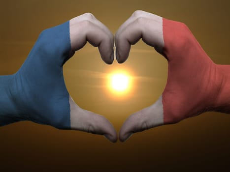 Gesture made by france flag colored hands showing symbol of heart and love during sunrise