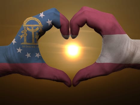 Gesture made by georgia flag colored hands showing symbol of heart and love during sunrise