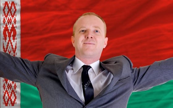 joyful investor spreading arms after good business investment in belarus, in front of flag