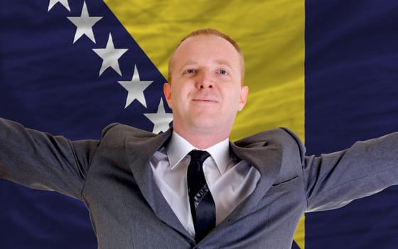 joyful investor spreading arms after good business investment in bosnia herzegovina, in front of flag