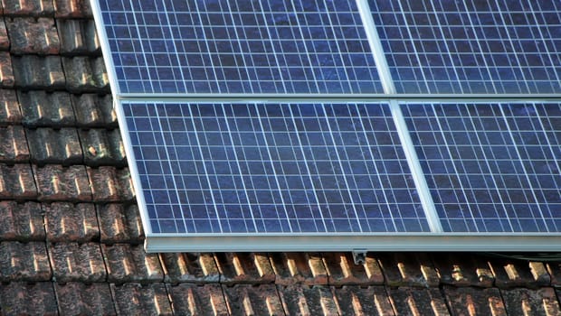 Several solar panels on an old roof made of brown tiles