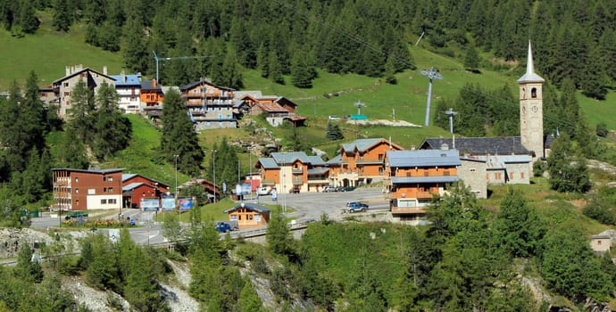 View of Tignes village in the Alps mountains with its houses and church among fir trees, France