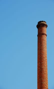 red brick industrial chimney against a blue sky background (plenty copy-space)