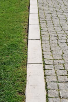 shallow depth of field on green grass and stone calcada pavement as a business concept (soft versus rough)