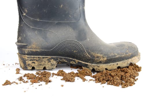 one muddy farmer boot and soil isolated on a white background