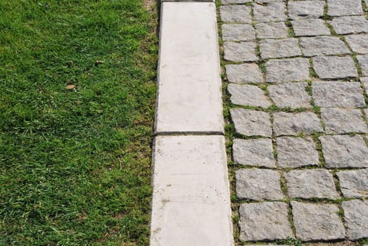 green grass and stone calcada pavement as a business concept (soft versus rough)