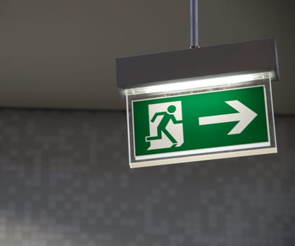 beautiful green emergency exit sign hanging on a ceiling