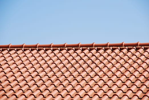 orange tiles on the roof of a house against blue sky background