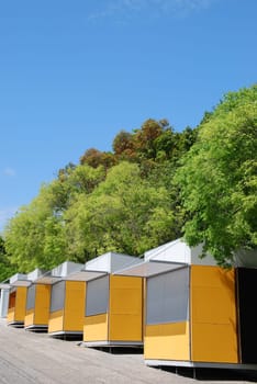 yellow kiosks shops against green trees and blue sky background