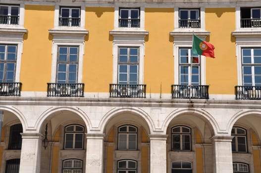 yellow building with portuguese flag surrounding Commerce Square in Lisbon, Portugal