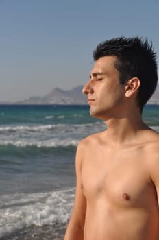 handsome young man getting suntan at Kos beach in Greece (blue sky)