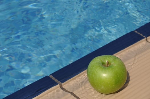 green apple at the pool side as a diet concept (healthy food and exercise)