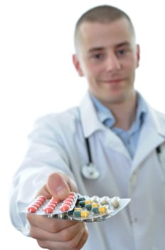 Young doctor offering many drugs. Isolated on white background.