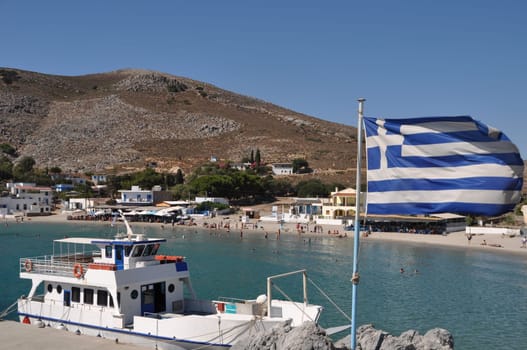 beautiful bay of Pserimos island with Greece flag