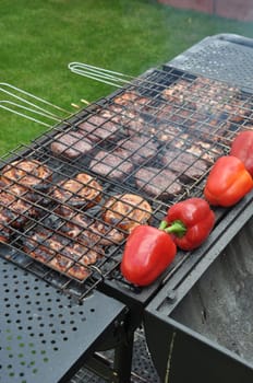 grilling fresh meat, sausages and peppers on a outdoor barbecue (shallow depth of field)