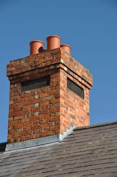 old brick chimney on black tile roof (blue sky)