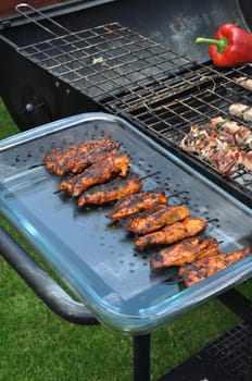 delicious chicken spits in a serving platter next to outdoor barbecue