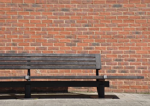 wooden bench against a brick wall building