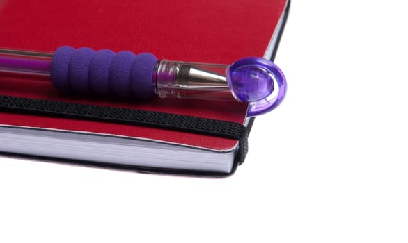red notebook diary or agenda and purple pen lying on the top (isolated on white background)