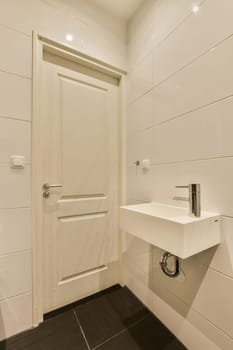 a white bathroom with black tile flooring and an open door leading to the toilet area in the shower room