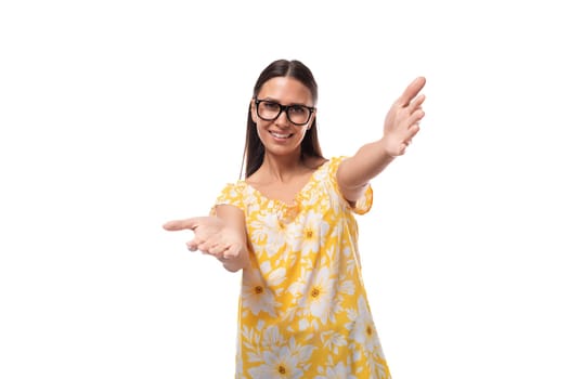 a young woman dressed in a yellow sundress and with glasses rejoices and smiles.