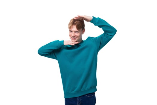 young satisfied red-haired man with a blue sweater on a white background.